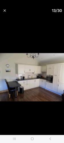cocina con armarios blancos y mesa negra en Clonard Cottage en Clonard