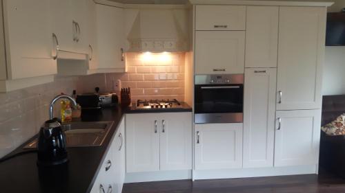 een keuken met witte kasten en een wastafel bij Clonard Cottage in Clonard