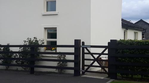 ein schwarzer Zaun vor einem weißen Haus in der Unterkunft Clonard Cottage in Clonard
