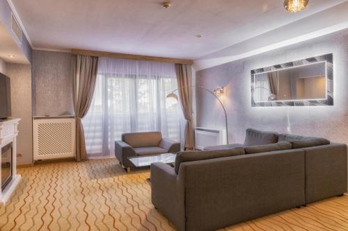 a living room with a couch and a chair at Malinowy Dwór Hotel Medical SPA in Świeradów-Zdrój