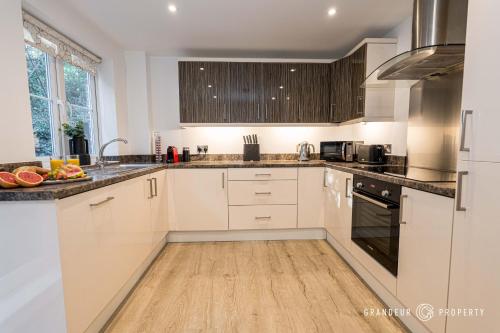 a kitchen with white cabinets and black appliances at Elegant townhouse, Westbourne, Sleeps 8, Parking - The Hideaway in Bournemouth