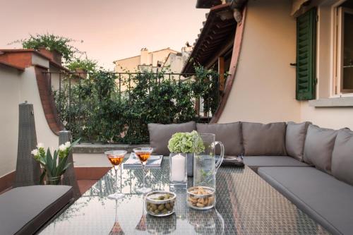 un patio con sofá y mesa de cristal en Tornabuoni Suites Collection Residenza D'Epoca, en Florencia