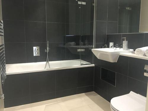 La salle de bains est pourvue d'une baignoire, d'un lavabo et de toilettes. dans l'établissement GRAND SERVICED APARTMENT*****, à Croydon