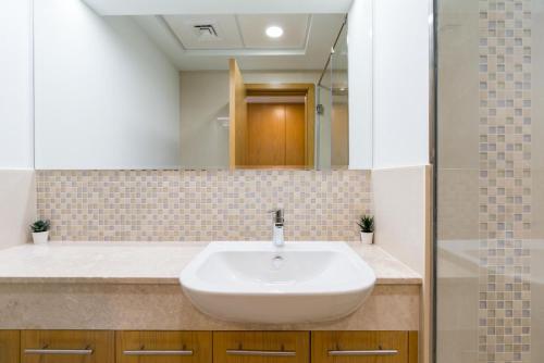 een badkamer met een witte wastafel en een spiegel bij Burj Khalifa View 2BR Spacious Bellevue Tower in Dubai