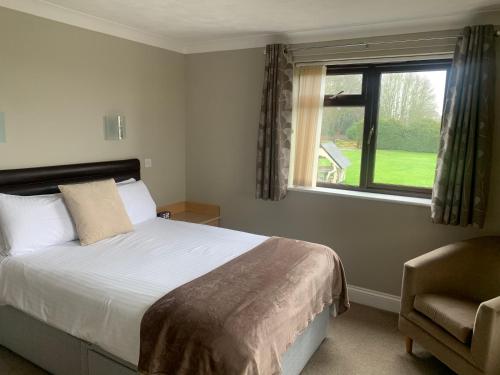 a bedroom with a bed and a window and a chair at Church Farm Guest House in Horsford