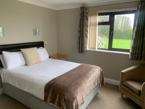 a bedroom with a bed and a window and a chair at Church Farm Guest House in Horsford