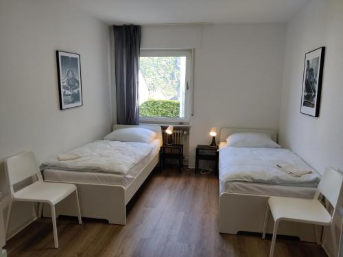 DWK: Monteurhaus Bad Salzig في بوبارد: سريرين في غرفة مع نافذة وكرسيين