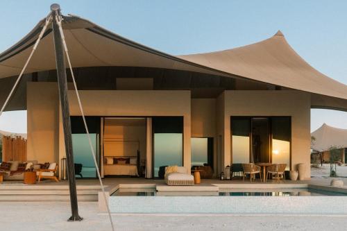 a villa with a canopy over a swimming pool at Our Habitas Ras Abrouq in Dukhān