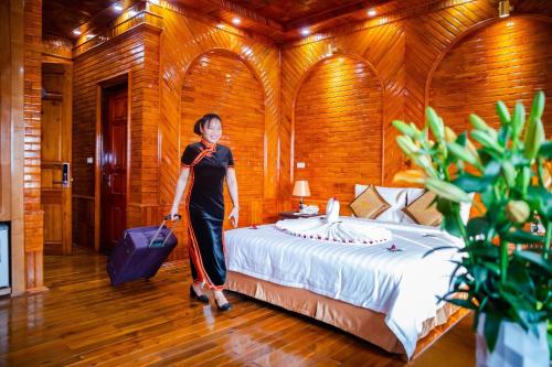 a woman is standing in front of a bed at Noi Bai The King Hotel in Sóc Sơn