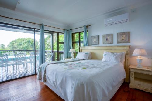 a bedroom with a white bed and a balcony at Campismo Ninho 29 in Ponta Malongane