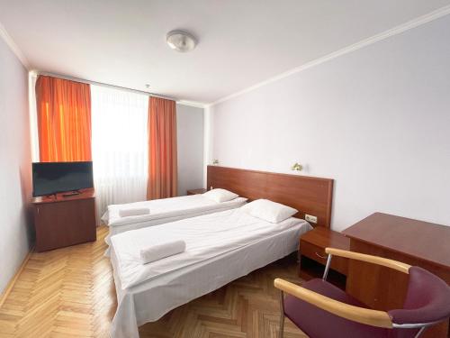 ルツカイにあるSvytyaz Hotelのベッド2台とデスクが備わるホテルルームです。