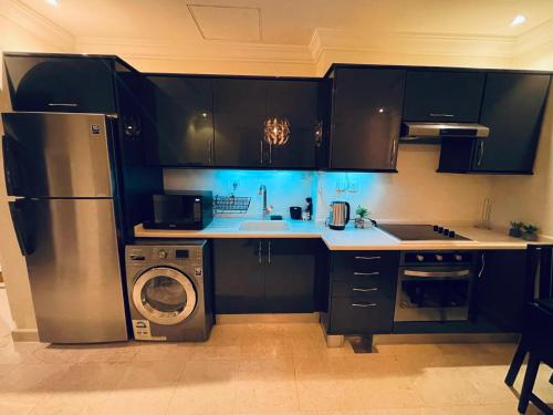 a kitchen with black cabinets and a washer and dryer at lovely one bedroom self entry in Jeddah