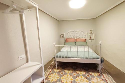 um pequeno quarto com uma cama branca num quarto em Acogedora casa en Llíria em Llíria