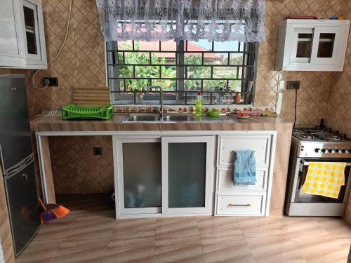 a kitchen with white cabinets and a sink and a window at Bethel Apartment in Oyarifa