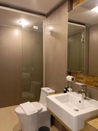 a bathroom with a sink and a toilet and a mirror at Wisdom Hotel & Residence in Rayong