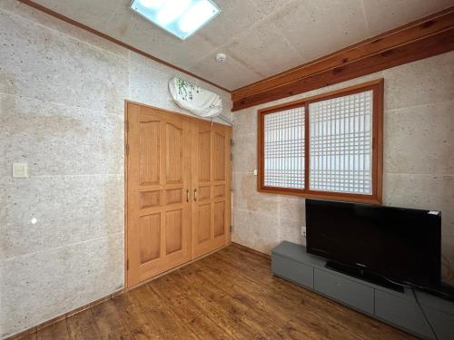 a living room with a television and a door at Sunset Hanok Stay in Suncheon