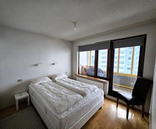 a bedroom with a bed and a chair and a window at Family penthouse with great view in Garðabær