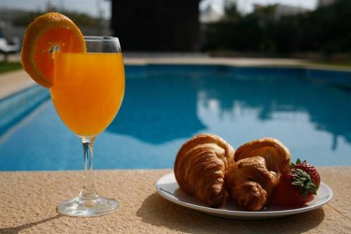 a plate of croissants and a glass of orange juice at Bonita Moradia c/ Piscina em SAGRES in Sagres
