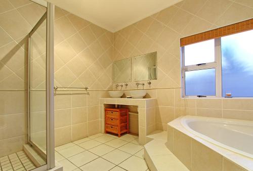 a bathroom with a tub and a sink and a mirror at Durham Close 31 by HostAgents in Bloubergstrand