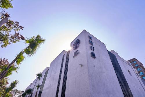 a tall building with a clock tower with palm trees at 和陽行館 Villa Bon Moment in Dayuan