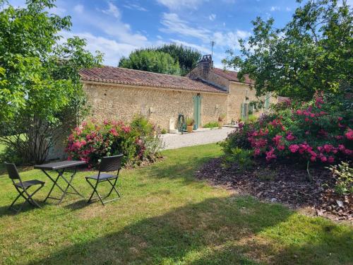a garden with two chairs and a table and flowers at Holiday Home Le Coustal by Interhome in Blanquefort-sur-Briolance