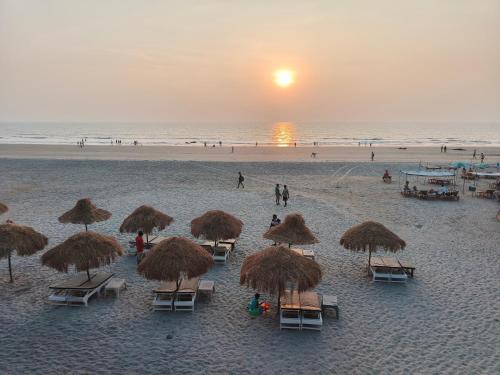 a group of chairs and straw umbrellas on a beach at Aqua Beach Resort Ashwem in Mandrem