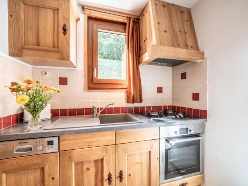 Una cocina con armarios de madera y un fregadero y una ventana. en Apartment Le Tetras-4 by Interhome, en Morzine