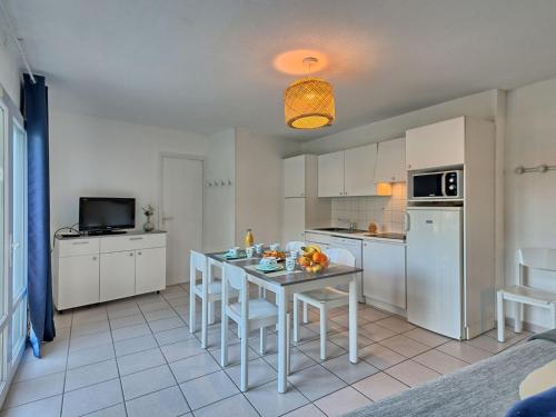 une cuisine avec des armoires blanches et une table avec des chaises dans l'établissement Holiday Home Hameau Océan-2 by Interhome, à La Parée Preneau