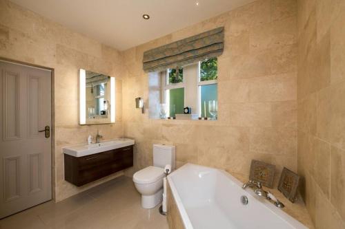 y baño con bañera, aseo y lavamanos. en 6* Royal Garden Suite Private Island Lake District, en Caton