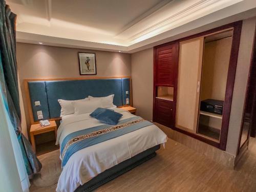 a bedroom with a large bed with a blue headboard at Hotel Royal Palace in Douala