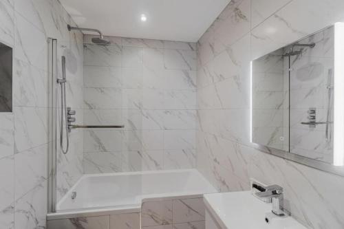 La salle de bains blanche est pourvue d'une baignoire et d'un lavabo. dans l'établissement 3BR Retreat, Allocated Parking, Private Garden, à Windsor
