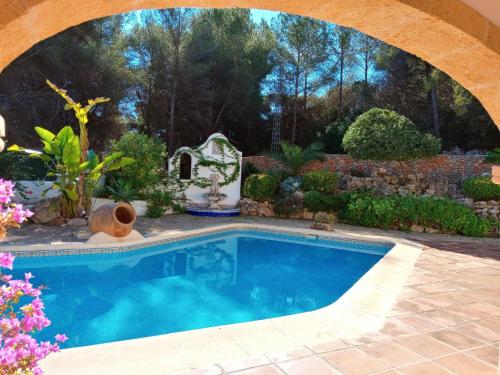 a swimming pool in a garden with an arch over it at Holiday Home Amadorio by Interhome in Benitachell