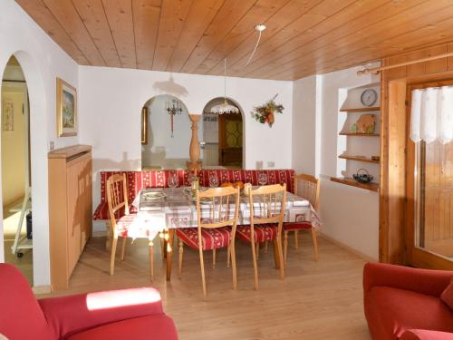 uma sala de jantar com uma mesa e cadeiras vermelhas em Apartment Deluca - PFS466 by Interhome em Pozza di Fassa