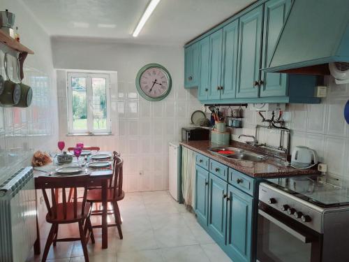 a kitchen with blue cabinets and a table and a clock at Coja Flores Beautiful River Beaches & Mountains in Coja