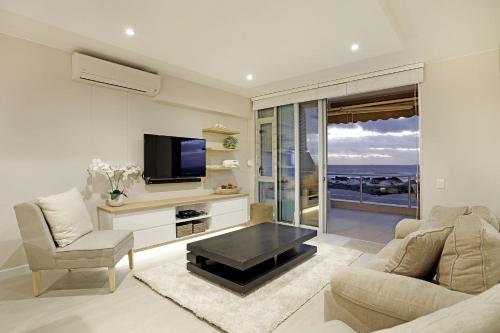 a living room with a tv and a couch and a table at Dolphin Beach H106 by HostAgents in Bloubergstrand