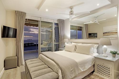 a bedroom with a large bed and a balcony at Dolphin Beach H106 by HostAgents in Bloubergstrand