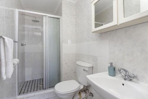 a bathroom with a toilet and a shower and a sink at Coral Island 102 in Bloubergstrand