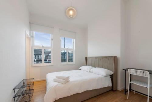 Stunning 1-bed Flat in London 20 mins from Central London في لندن: غرفة نوم بسرير ومكتب ونوافذ