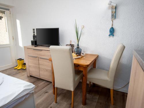 Una mesa de comedor con dos sillas y un televisor. en Apartment Schwalbennest V by Interhome, en Norddeich