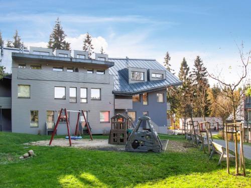 a yard with playground equipment in front of a house at Apartment Resident Harrachov B - HRA170 by Interhome in Harrachov
