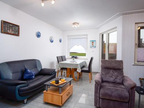 ein Wohnzimmer mit einem Sofa, einem Tisch und Stühlen in der Unterkunft Apartment Seerose by Interhome in Norddeich