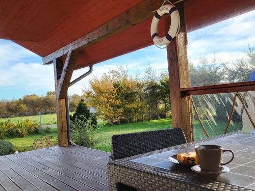a table with a cup of coffee on a deck at Holiday Home Modrzewiowy Zakątek by Interhome in Smołdziński Las