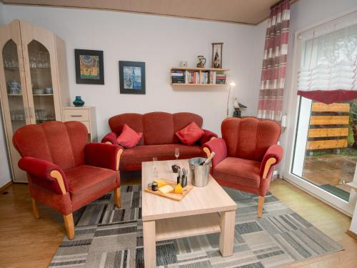 ein Wohnzimmer mit 2 roten Stühlen und einem Tisch in der Unterkunft Holiday Home Wind by Interhome in Norddeich