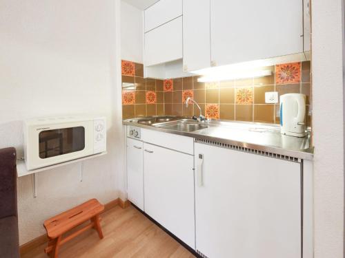 a small kitchen with white cabinets and a microwave at Studio Combire 104 by Interhome in Les Collons