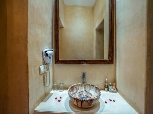 a bathroom with a bowl sink and a mirror at Riad Maialou & SPA in Marrakech