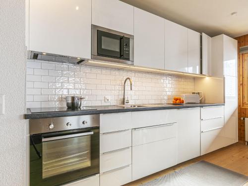 a kitchen with white cabinets and a sink and a microwave at Apartment Brocard by Interhome in Val dʼIlliez