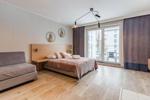 una camera da letto con un letto, un divano e una finestra di Langgarten Apartments by Little Heaven a Danzica