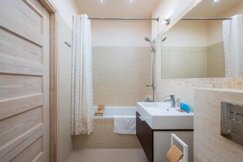 La salle de bains est pourvue d'un lavabo blanc et d'une douche. dans l'établissement Obrzeżna Beige Apartment, à Varsovie