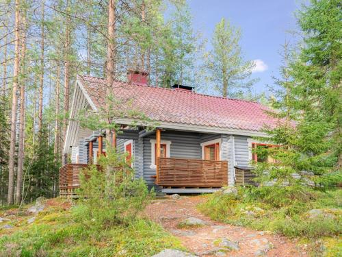 uma casa cinzenta com um telhado vermelho na floresta em Holiday Home Kanerva by Interhome em Ahmovaara