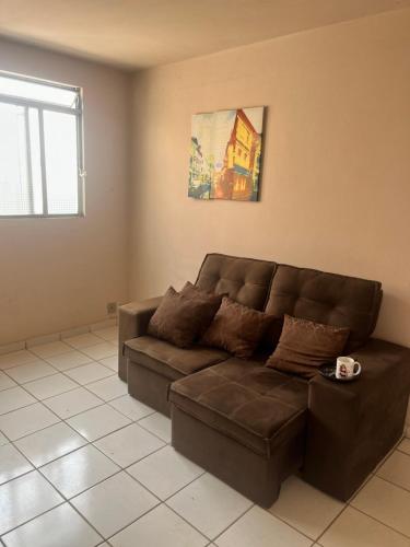 a living room with a brown couch and a window at QUARTO PRIVADO PARA ALGUEL (Diária). in Goiânia